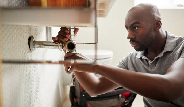 a male plumber fixing a pipe connection from TMK Plumber Austin in Austin, TX Plumber near me